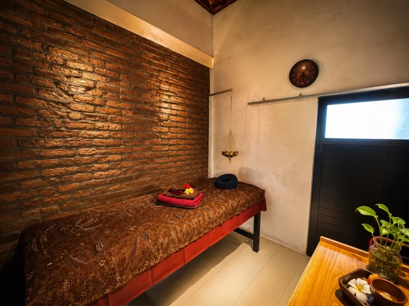 Tranquil spa treatment room with brick wall and massage bed